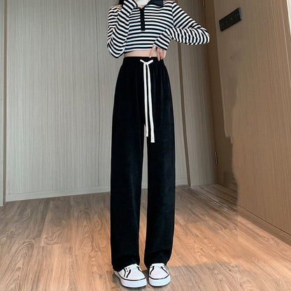 Schwarz-weiße gestreifte Langarm-Crop-Top und schwarze weite Hose mit Kordelzug, getragen von einer Person in einem modernen, minimalistischen Raum.