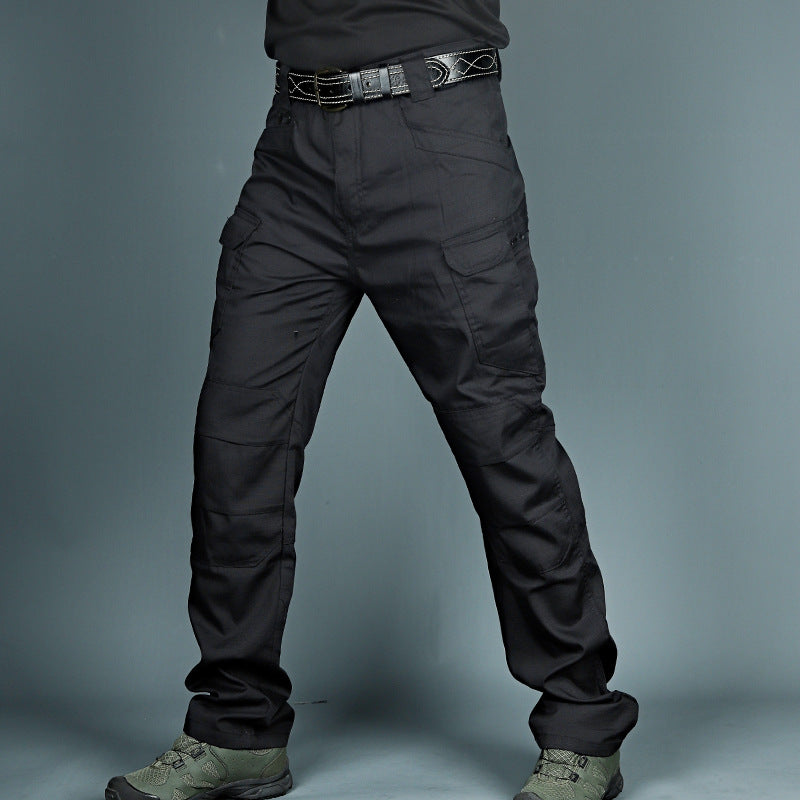 Schwarze taktische Hose mit mehreren Taschen, robustem Gürtel und grünen Stiefeln. Ideal für Outdoor-Aktivitäten und Arbeitseinsätze.