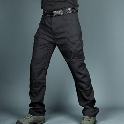 Schwarze taktische Hose mit mehreren Taschen, robustem Gürtel und grünen Stiefeln. Ideal für Outdoor-Aktivitäten und Arbeitseinsätze.