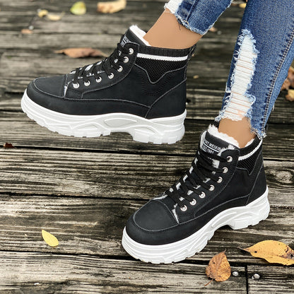 Schwarze Damen-Sneakerstiefel mit weißer Sohle auf Holzdeck, getragen mit zerrissenen Jeans. Modische Herbstschuhe, Outdoor-Style.