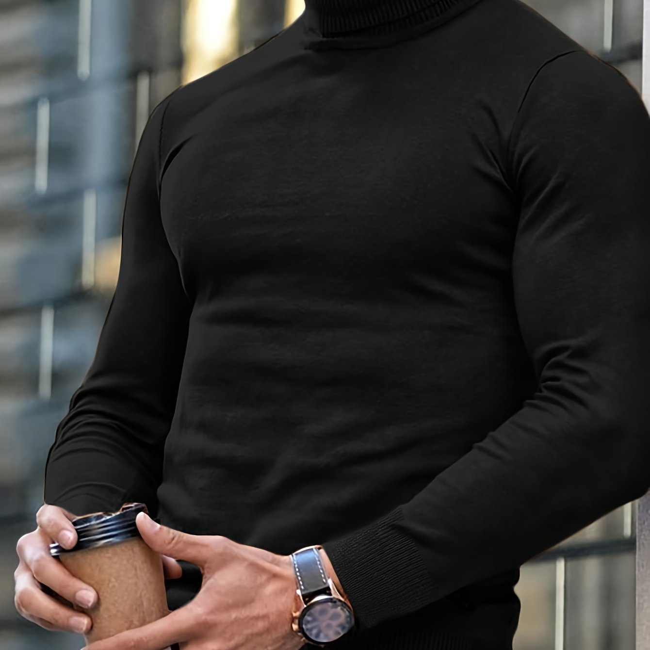 Mann in schwarzem Rollkragenpullover hält Kaffeebecher, trägt Armbanduhr. Urbaner Hintergrund, modischer Look, Herbstmode, stilvoll gekleidet.