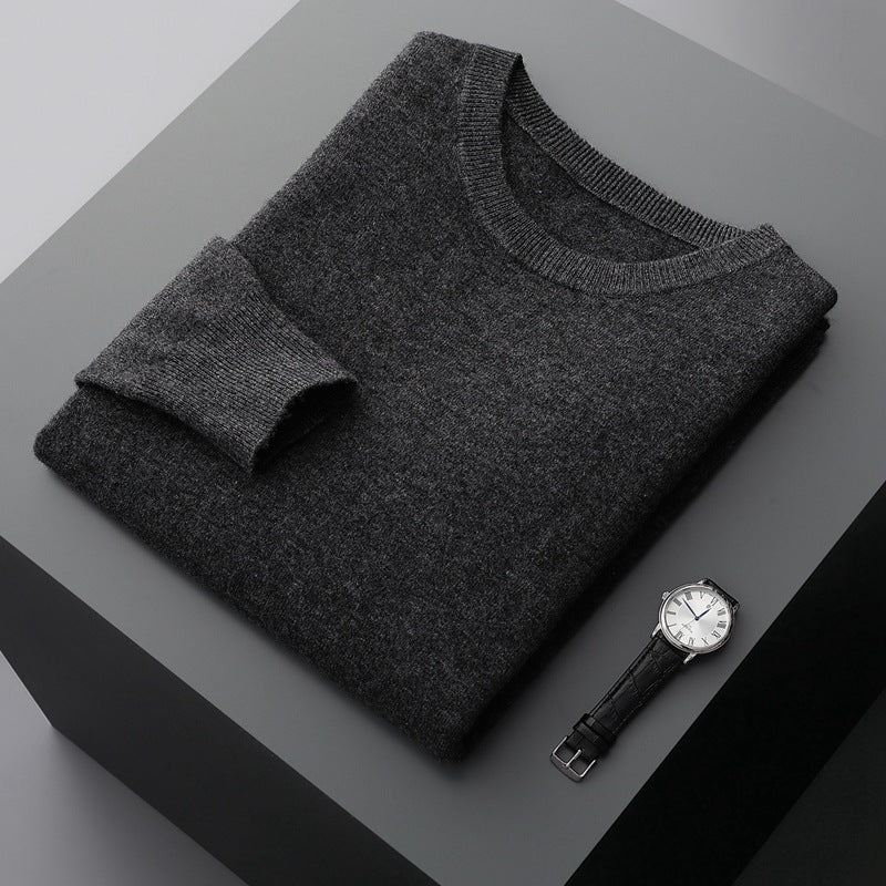 Grauer Kaschmirpullover auf schwarzem Tisch neben eleganter Armbanduhr. Luxuriöse Herrenmode, stilvolles Design, hochwertige Materialien.