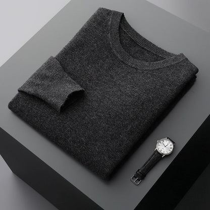 Grauer Kaschmirpullover auf schwarzem Tisch neben eleganter Armbanduhr. Luxuriöse Herrenmode, stilvolles Design, hochwertige Materialien.