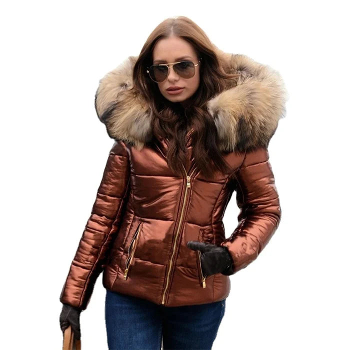 Frau in glänzender, kupferfarbener Daunenjacke mit Fellkapuze, Sonnenbrille und Jeans. Wintermode, stilvolle Damenjacke, Outdoor-Bekleidung.