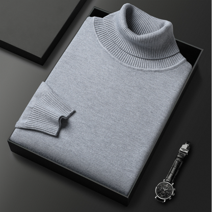 Grauer Rollkragenpullover aus Kaschmir in schwarzer Geschenkbox, daneben eine elegante Armbanduhr. Luxuriöse Herrenmode, stilvolles Accessoire.