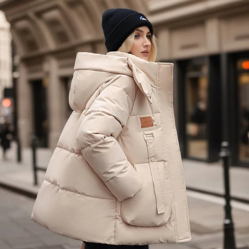 Frau in beiger Daunenjacke und schwarzer Mütze auf städtischer Straße. Wintermode, warme Kleidung, stilvolle Damenjacke, Outdoor-Bekleidung.