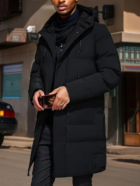 Mann in schwarzem Wintermantel hält Smartphone, steht auf städtischer Straße. Stilvolle Wintermode, urbane Kulisse, moderne Herrenbekleidung.