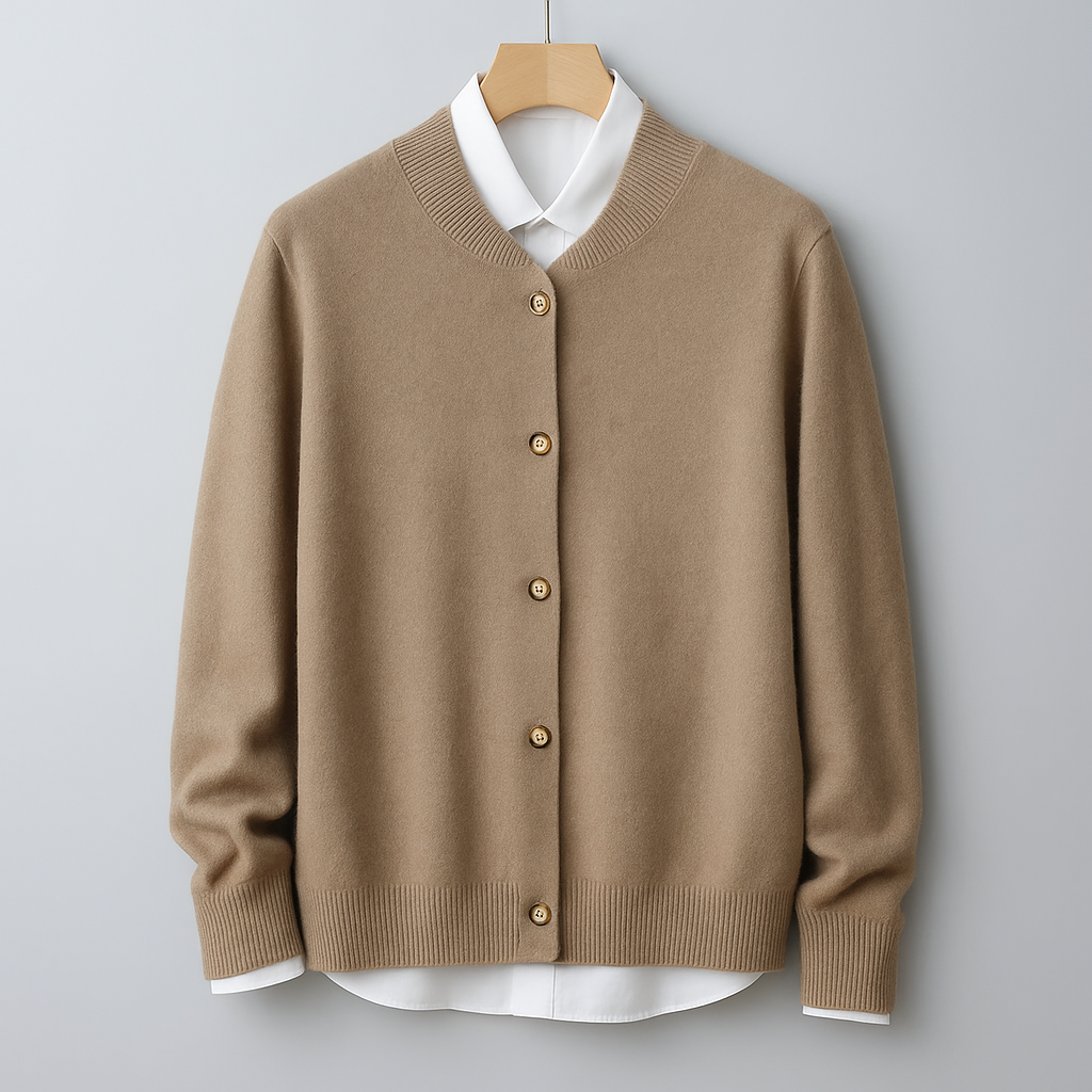 Beige Strickjacke aus Kaschmir mit Knopfleiste, hängend an einem Kleiderbügel vor grauem Hintergrund. Elegante Damenmode, Herbstkollektion.
