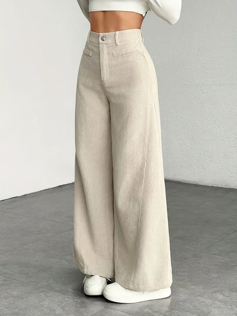 Damenmode: Beige Cordhose mit weitem Bein, kombiniert mit weißem Crop-Top und Sneakern. Trendige Herbstmode, lässiger Stil, Streetwear-Look.