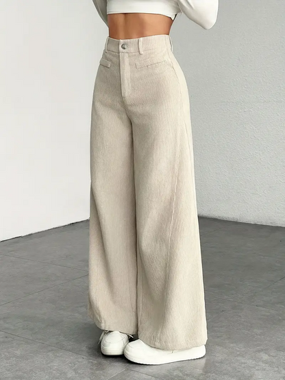Damenmode: Beige Cordhose mit weitem Bein, kombiniert mit weißem Crop-Top und Sneakern. Trendige Herbstmode, lässiger Stil, Streetwear-Look.
