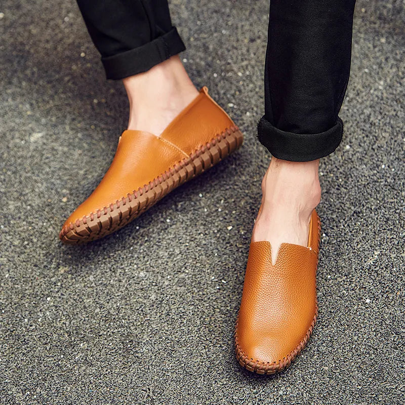 Herren braune Leder-Slipper auf Asphalt, modische Freizeitschuhe, bequeme Sommerschuhe, stilvolle Herrenschuhe, Nahaufnahme.