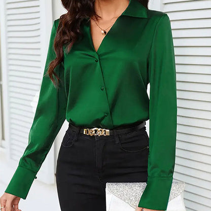Frau in grüner Bluse und schwarzer Hose, hält silberne Clutch. Elegante Mode, stilvolle Damenbekleidung, modernes Outfit für Büro oder Abend.