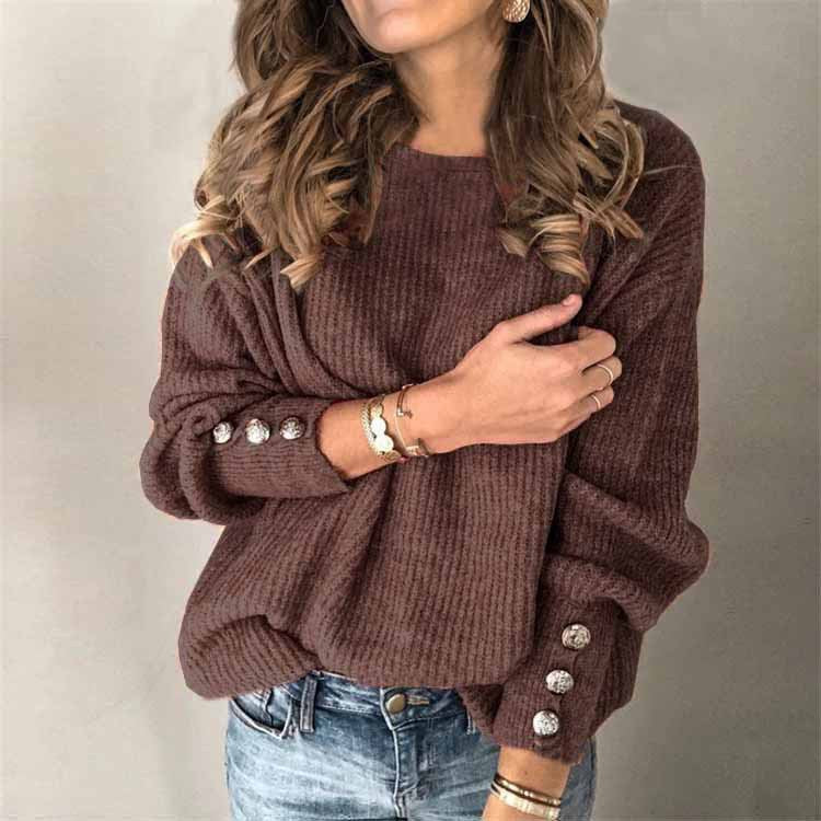 Brauner Strickpullover mit Knöpfen an den Ärmeln, getragen von einer Frau mit welligem Haar. Modischer Herbstlook, ideal für kühle Tage.