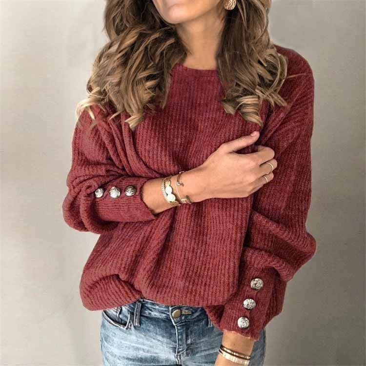 Frau in rotem Strickpullover mit Knöpfen an den Ärmeln, trägt Jeans und Schmuck. Modetrend, Herbstmode, Damenbekleidung, lässiger Stil.