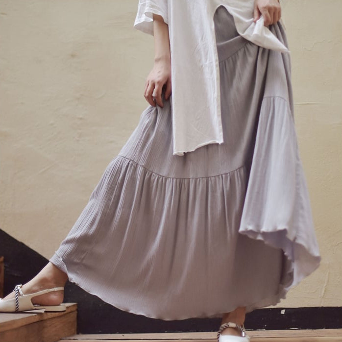 Lange graue Plissee-Rock, getragen von Person in weißem Oberteil, modisch und elegant, ideal für Sommermode und Freizeitkleidung.