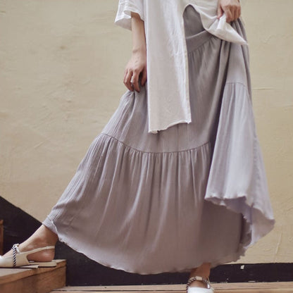 Lange graue Plissee-Rock, getragen von Person in weißem Oberteil, modisch und elegant, ideal für Sommermode und Freizeitkleidung.