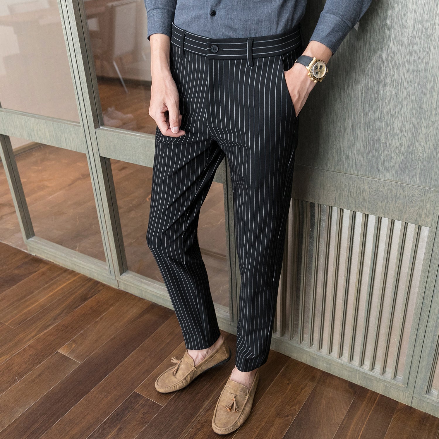 Mann in gestreifter Anzughose und braunen Mokassins, steht auf Holzboden. Elegante Herrenmode, Business-Look, stilvolle Herrenhose.