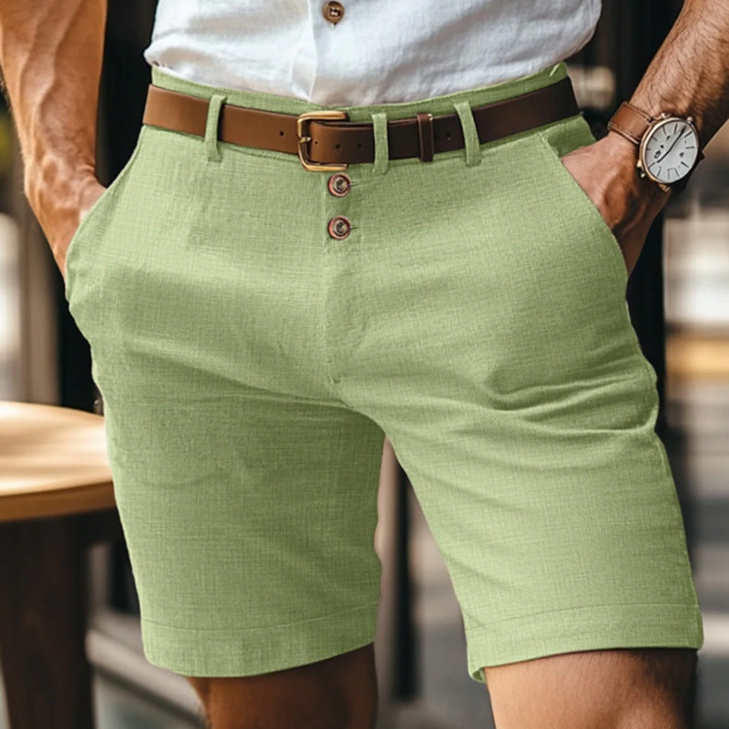 Mann in grüner Leinen-Shorts mit braunem Ledergürtel und weißem Hemd. Sommermode, Herrenbekleidung, stilvolle Freizeitkleidung.