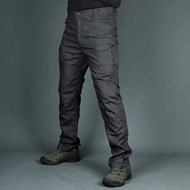 Graue taktische Hose mit mehreren Taschen, getragen von einer Person, kombiniert mit olivgrünen Wanderschuhen. Ideal für Outdoor-Aktivitäten.