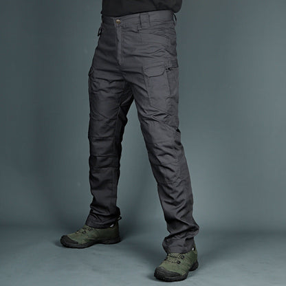 Graue taktische Hose mit mehreren Taschen, getragen von einer Person, kombiniert mit olivgrünen Wanderschuhen. Ideal für Outdoor-Aktivitäten.