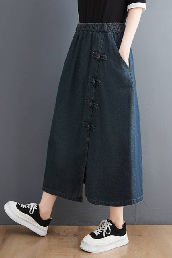 Damenmode: Langer, dunkelblauer Jeansrock mit seitlichen Knöpfen, kombiniert mit schwarzen Sneakern. Trendiger, lässiger Look für den Alltag.