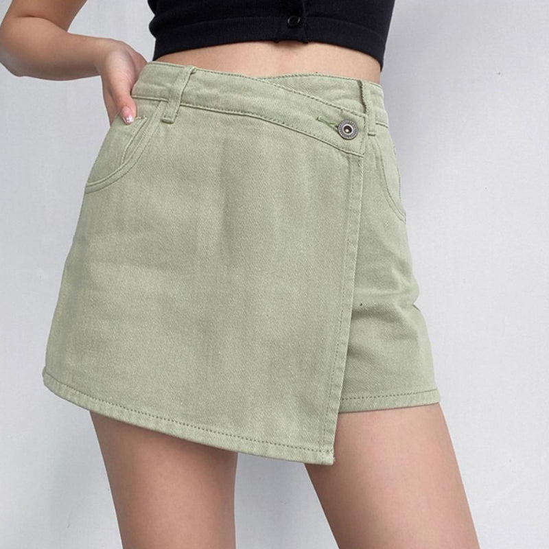 Frau trägt grünen asymmetrischen Jeansrock, kombiniert mit schwarzem Top. Modetrend, Damenmode, Sommeroutfit, stilvoller Look.