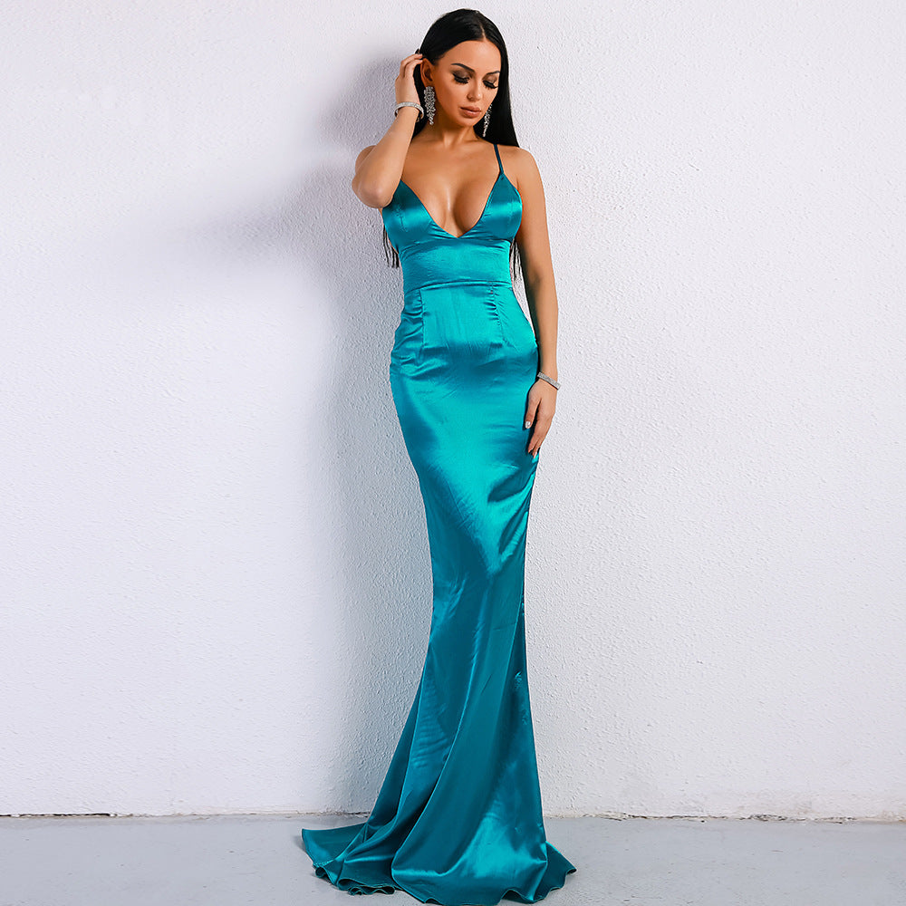 Frau in elegantem, türkisfarbenem Abendkleid mit tiefem Ausschnitt, posiert vor weißer Wand. Perfekt für Mode, Abendmode, Ballkleider.