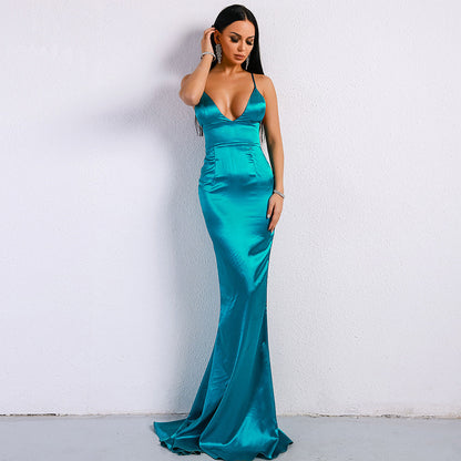 Frau in elegantem, türkisfarbenem Abendkleid mit tiefem Ausschnitt, posiert vor weißer Wand. Perfekt für Mode, Abendmode, Ballkleider.