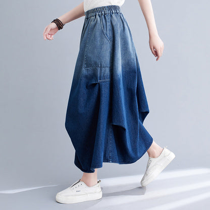 Frau trägt langen, blauen Jeansrock mit asymmetrischem Design und weißen Sneakers. Modetrend, Damenmode, lässiger Stil, Denim-Rock.