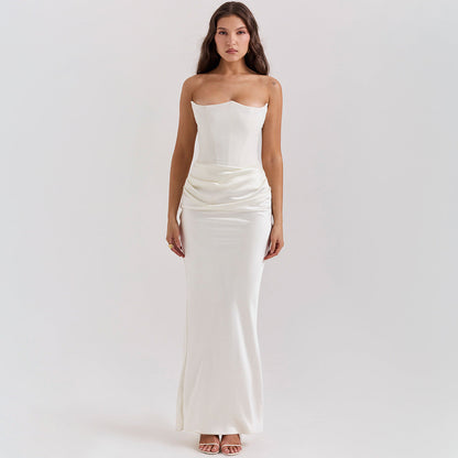 Frau in elegantem, trägerlosem weißen Abendkleid mit drapiertem Rock, stehend vor neutralem Hintergrund. Perfekt für Hochzeiten oder formelle Anlässe.