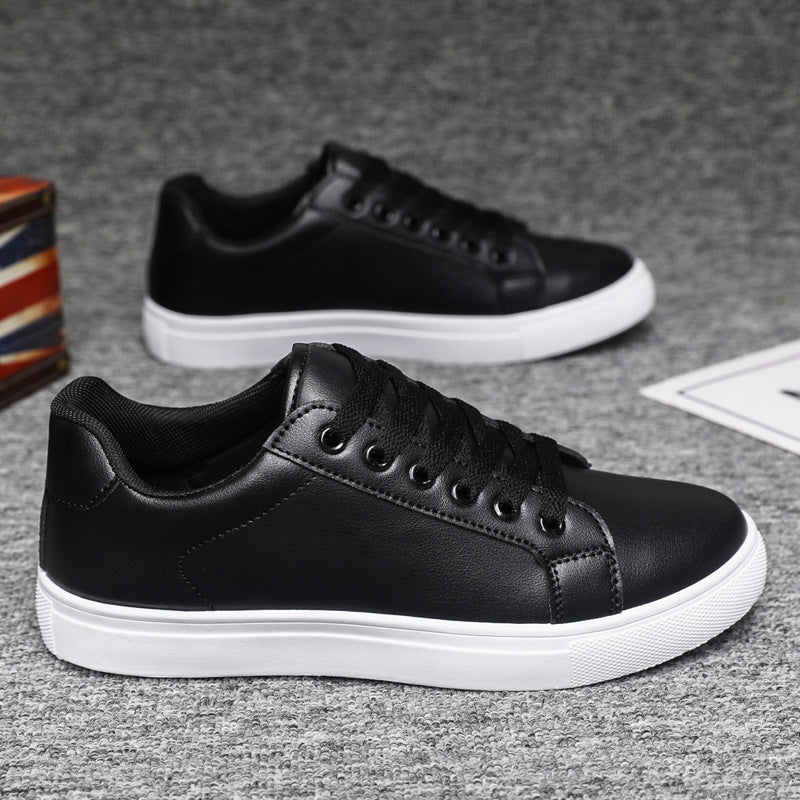 Schwarze Sneaker aus Leder mit weißer Sohle auf grauem Teppich. Modische Herrenschuhe, ideal für Freizeit und Alltag.