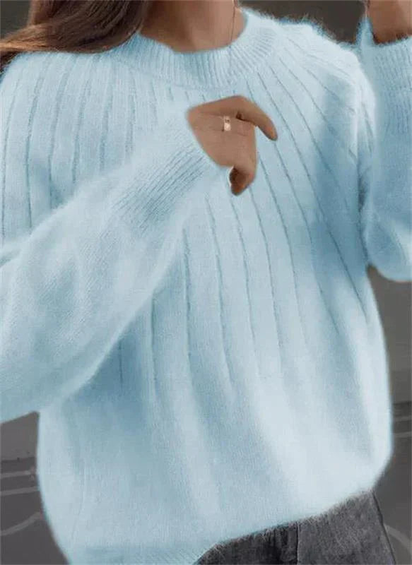Frau in hellblauem Strickpullover, weiches Material, modisches Design, Herbstmode, gemütlicher Look, grauer Hintergrund.