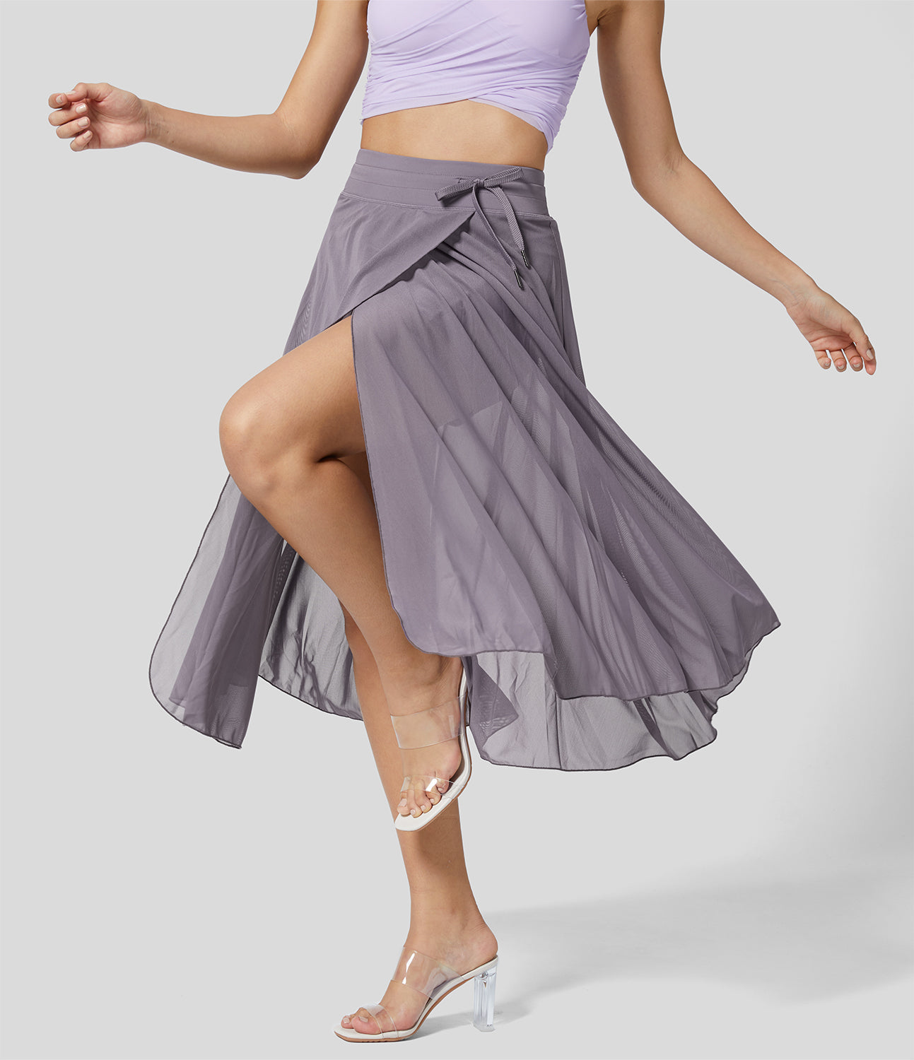 Frau in lila Wickelrock und durchsichtigem Absatzschuh, Tanzpose. Moderner, eleganter Damenrock, ideal für Ballett oder Tanz.