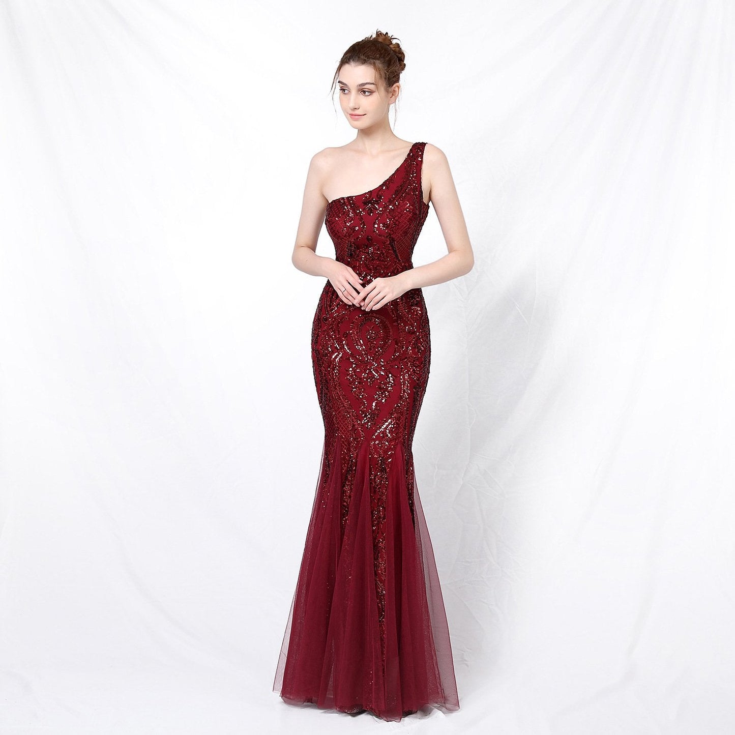 Frau in elegantem, einarmigem, rotem Abendkleid mit Pailletten, posiert vor weißem Hintergrund. Perfekt für Gala, Ball oder Abendveranstaltung.