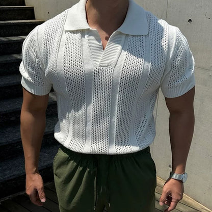 Mann in weißem Strick-Poloshirt und grüner Hose, steht vor Betonwand. Modetrend, Sommeroutfit, Herrenmode, lässiger Stil.
