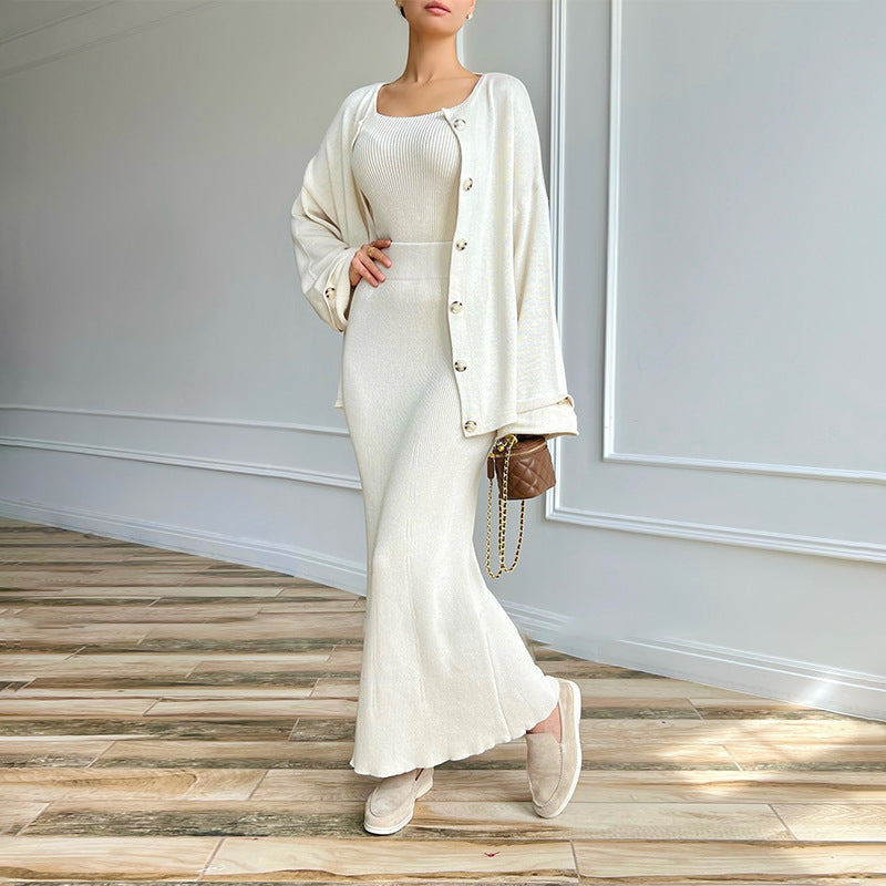 Elegantes Damen-Outfit in Creme: Strickkleid mit passender Strickjacke, braune Handtasche, beiger Boden, moderne Mode, stilvoller Look.