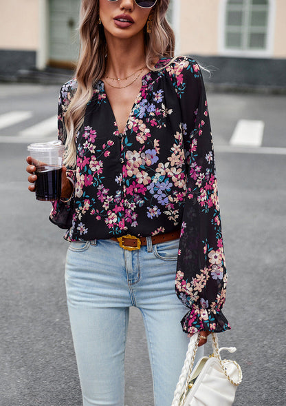 Frau in schwarzer, geblümter Bluse und blauer Jeans, hält ein Getränk und eine weiße Tasche. Modetrend, lässiger Streetstyle, Frühlingsmode.