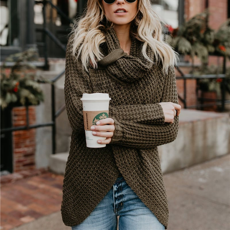 Blonde Frau in Strickpullover hält Starbucks-Becher, trägt Sonnenbrille, steht vor Backsteingebäude. Wintermode, Kaffee, urbaner Stil.