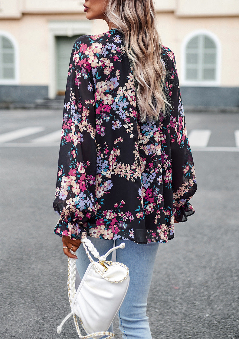 Frau in schwarzer, geblümter Bluse und blauer Jeans, hält weiße Handtasche. Modetrend, Streetstyle, lässiges Outfit, florales Design.