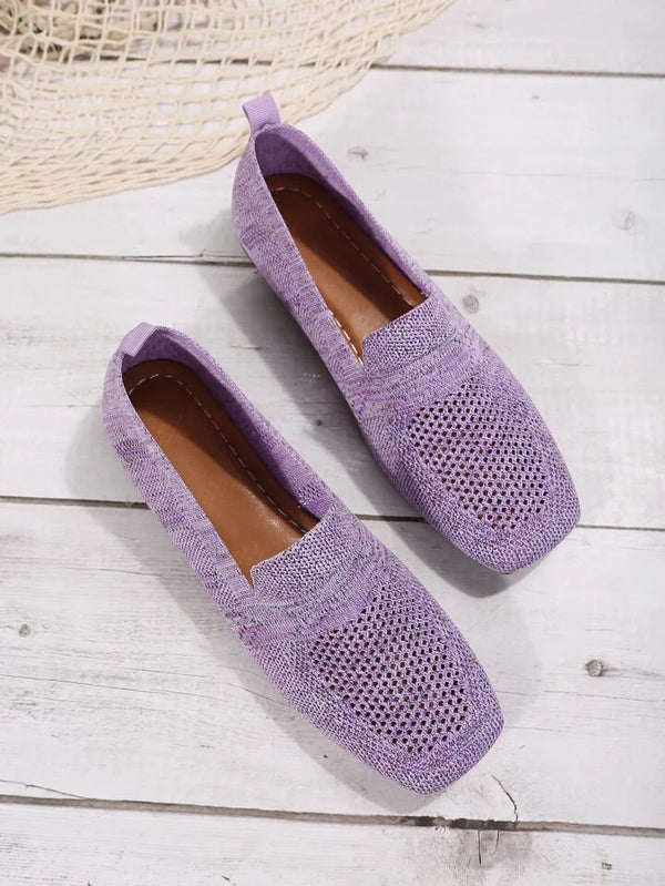 Lila Mokassins aus Strickmaterial auf Holzboden, modische Damen-Slipper, atmungsaktiv und bequem, ideal für Frühling und Sommer.