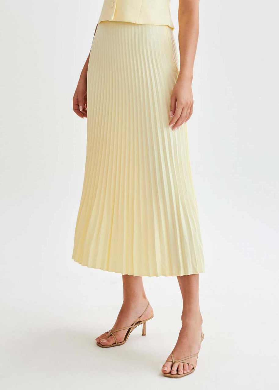 Eleganter gelber Plisseerock, knöchellang, kombiniert mit Sandaletten. Perfekt für Sommermode und stilvolle Outfits.