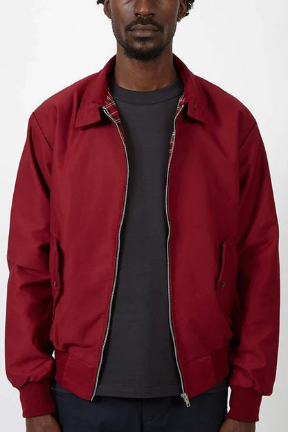 Mann trägt rote Harrington-Jacke mit Reißverschluss, schwarzem T-Shirt und dunkler Hose. Modische Herrenbekleidung, lässiger Stil.