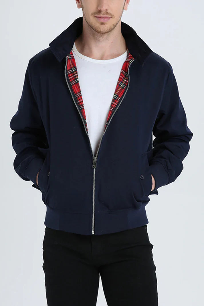 Mann trägt dunkelblaue Harrington-Jacke mit rotem Karofutter, weißem T-Shirt und schwarzer Hose. Modische Herrenbekleidung, lässiger Stil.