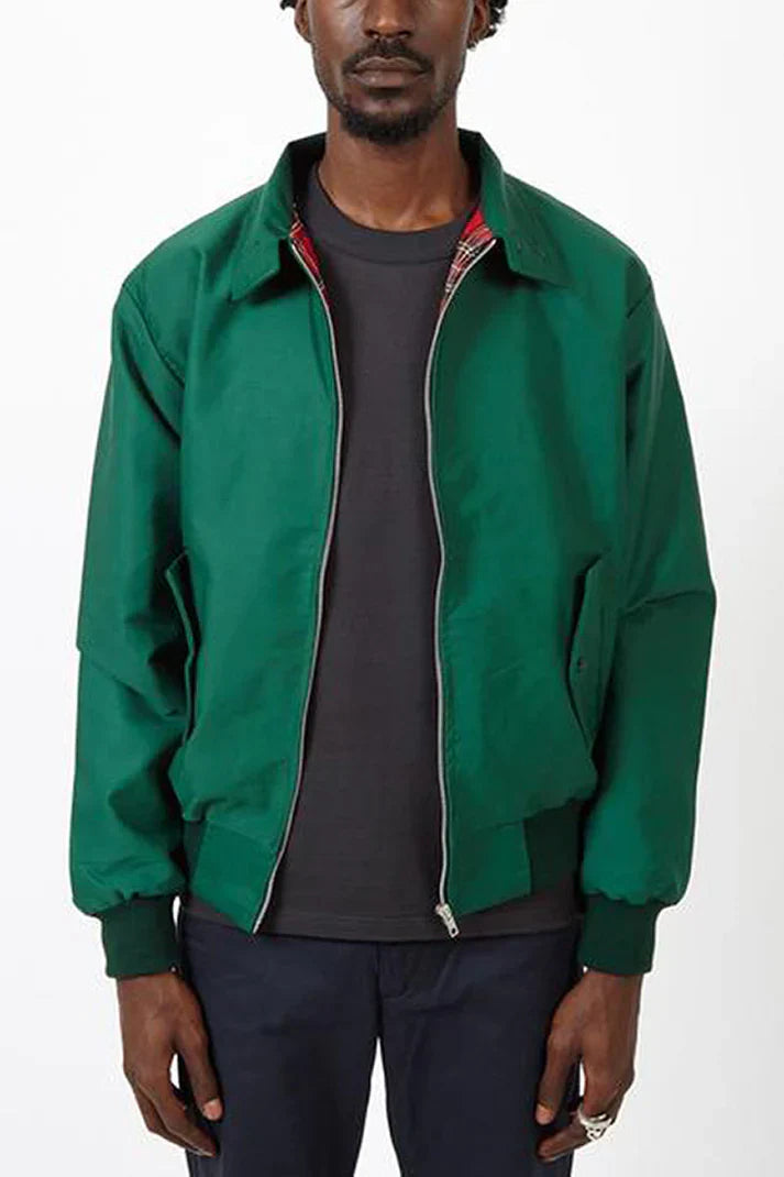 Mann trägt grüne Harrington-Jacke mit Reißverschluss, schwarzes T-Shirt und dunkle Hose. Modetrend, Herrenbekleidung, lässiger Stil.