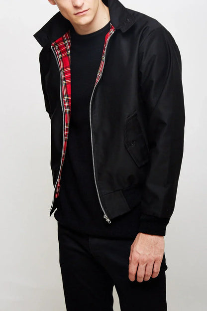 Mann trägt schwarze Harrington-Jacke mit rotem Karofutter, Reißverschluss und Taschen. Modische Herrenbekleidung, klassischer Stil, Herbstmode.