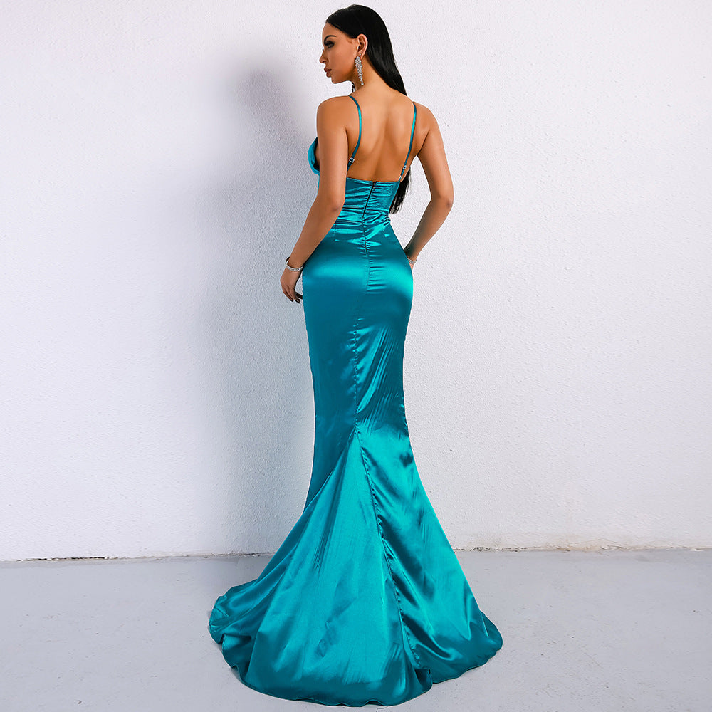 Frau in elegantem, türkisfarbenem Abendkleid mit Spaghettiträgern und Schleppe, steht vor weißer Wand. Perfekt für Gala, Ball oder Abendveranstaltung.