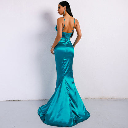 Frau in elegantem, türkisfarbenem Abendkleid mit Spaghettiträgern und Schleppe, steht vor weißer Wand. Perfekt für Gala, Ball oder Abendveranstaltung.