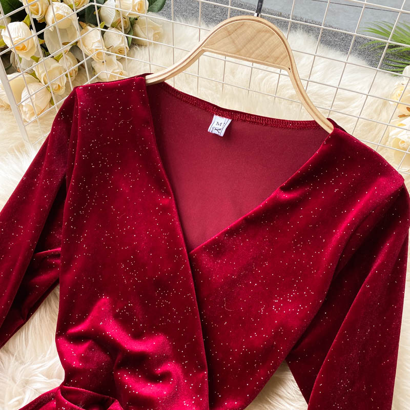 Rotes Samtkleid mit Glitzer, auf Kleiderbügel vor Blumenhintergrund. Elegantes Abendkleid, langärmelig, ideal für festliche Anlässe.