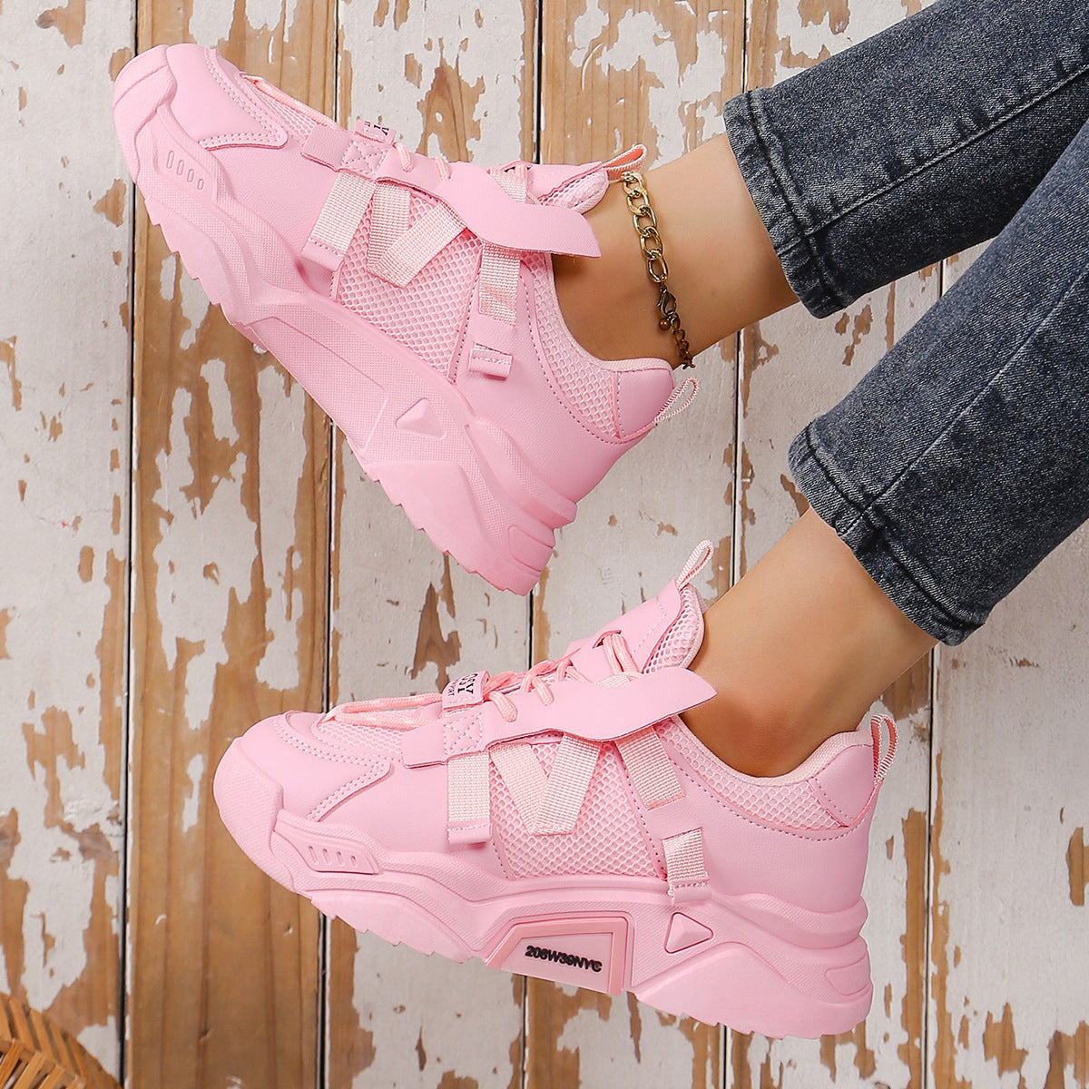Rosa Sneaker auf Holzboden, modisch und sportlich, mit dicker Sohle und Mesh-Details. Perfekt für Damenmode und Streetwear-Trends.