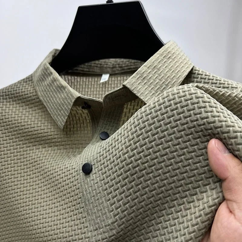 Beige Herrenhemd mit strukturiertem Waffelmuster, schwarzer Knopfleiste, auf einem Kleiderbügel präsentiert. Elegantes Design, hochwertige Baumwolle.
